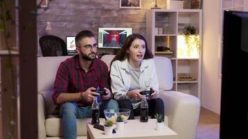 alegre jovem casal sentado em sofá e jogando vídeo jogos em televisão. feliz relação video