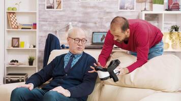 sobrino demostración su abuelo cómo a utilizar vr auriculares en vivo habitación. video