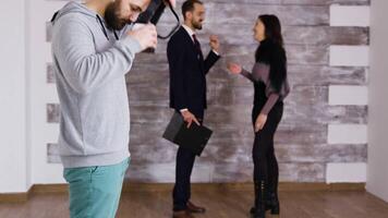 uomo utilizzando virtuale la realtà occhiali nel nuovo vuoto appartamento mentre donna è parlando con vero tenuta agente nel il sfondo. video