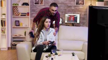 novio Ayudar su Novia a ganar a vídeo juegos en televisión. Pareja jugando vídeo juegos. video