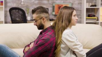 Distant couple sitting back to back on the couch after an argument. Boyfriend and girlfriend problems. video