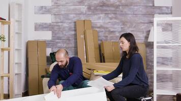 Couple assembling furniture in their new apartment. Couple do a high five after job done. video