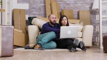 couple séance sur le sol de Nouveau appartement et en utilisant portable pour en ligne achats. video