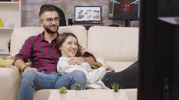 couple séance sur le canapé et en riant tandis que en train de regarder la télé. video