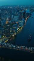 hermosa noche paisaje urbano de nuevo York en luces. zumbido imágenes terminado el río, navegación barco y puente. vertical vídeo video