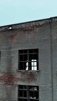 alt Backstein Fabrik Gebäude. Kommen näher zu das Haus mit gebrochen Fenster, leeren innen. Blau Himmel Hintergrund. Vertikale Video