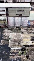 Warehouses of an old plant. Aerial perspective on the wrecked roof of a long empty warehouse in the industrial area. Vertical video