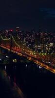 Wonderful Queensboro Bridge lit in green and orange. New York scenery full of lights at night time. Top view. Vertical video