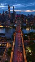 maravilloso ver de el ciudad a viniendo noche. Queensboro puente en luces con carros paso a lo largo de. paisaje urbano con rascacielos a fondo. vertical vídeo video