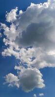 Beautiful soft light clouds transforming in the bright rays of summer sun. Low angle view timelapse. Vertical video