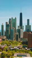 Green residential area with low multi-storied buildings. Modern beautiful skyscrapers against blue lake surface at backdrop. Vertical video