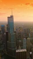 Gorgeous Chicago in the rays of setting sun. Endless city panorama at the backdrop of orange skies. Aerial view. Vertical video