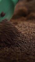 Candies covered with liquid chocolate being coated with cocoa and nuts. Spatula turning over the sweets to cover them with sprinkling. Close up. Vertical video