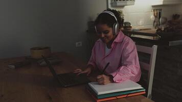 uma mulher dentro uma Rosa Jaqueta é sentado às uma mesa com uma computador portátil video