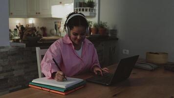 ein Frau im ein Rosa Jacke ist Sitzung beim ein Tabelle mit ein Laptop video