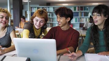 un grupo de multirracial estudiantes estudiando utilizando ordenador portátil en un biblioteca video