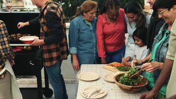 a group of people standing around a table with a salad video