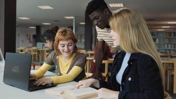 un' gruppo di multirazziale studenti studiando utilizzando il computer portatile nel un' biblioteca video