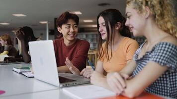 un' gruppo di multirazziale studenti studiando utilizzando il computer portatile nel un' biblioteca video