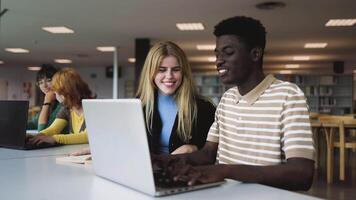 un' gruppo di multirazziale studenti studiando utilizzando il computer portatile nel un' biblioteca video