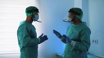 dois pessoas dentro médico protetora ternos em pé dentro frente do uma azul luz video