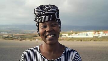 a africano mulher com uma cabeça cachecol sorrisos às a Câmera video