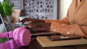 une femme travail sur sa portable avec rose casque de musique à côté de sa video