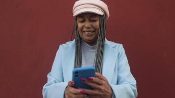 een vrouw met dreadlocks en een roze hoed is op zoek Bij haar telefoon video