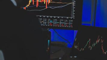 Businessman analyzing a graphic of a stock exchange chart. Back of the head of a young male businessman looking at a stock diagram on the big screen of the computer video