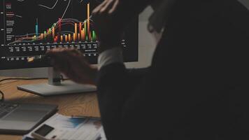 Businessman analyzing a graphic of a stock exchange chart. Back of the head of a young male businessman looking at a stock diagram on the big screen of the computer video