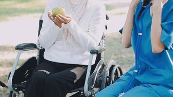 Midsection of female nurse checking blood pressure of woman sitting on wheelchair in clinic video