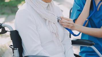 Midsection of female nurse checking blood pressure of woman sitting on wheelchair in clinic video