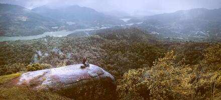 Women travel sit on a cliff on a rich forest mountain. Asia Tropical photo