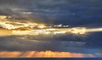 Dramatic thunderclouds over mediterranean sea with sun rays breaking through photo