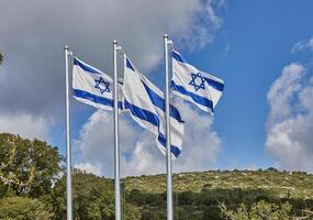 Four Israeli flags proudly waving under the blue sky with hills in the background photo