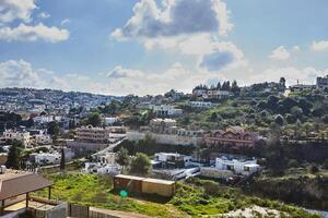 A scenic view of a town in the countryside with a blue sky and white clouds in the background photo