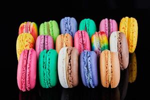 Assorted colorful macarons folded and arranged on a black surface with reflection photo