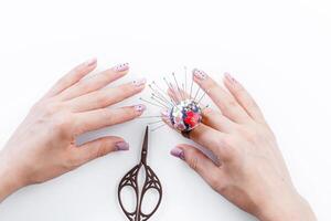 a ring with a small pillow for needles on a hand and scissors on a white background photo
