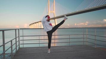 a woman in a hoodie and red gloves is exercising on a dock video