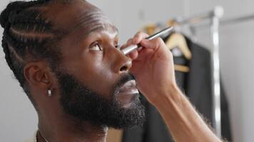 a man with a beard is getting his makeup done video