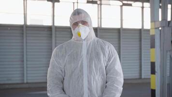 a man in a white protective suit is standing looking at the camera video