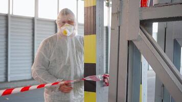 a man in a protective suit and mask rolling out the red and white tape video