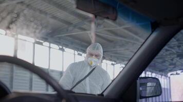 a man in a white protective suit and mask is spraying the car with antiseptic video