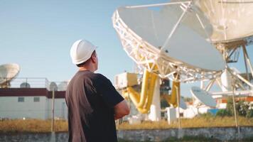 ein Mann im ein schwer Hut suchen beim Satellit Geschirr video