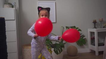 en liten flicka är spelar med en röd ballong video