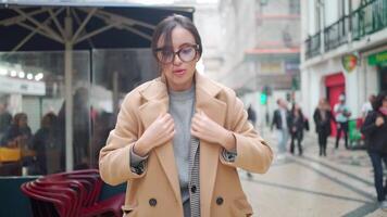 a woman in glasses and coat is walking down the street video