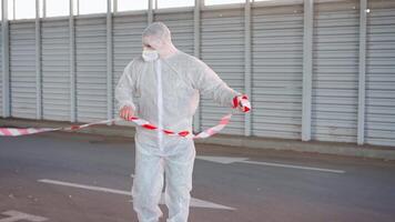 uma homem dentro uma protetora terno e mascarar rolando Fora a vermelho e branco fita video