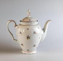 Porcelain teapot with floral ornament in classic style on white background. Old-style, retro, vintage, porcelain jug. photo