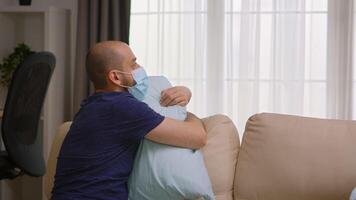 Mann infiziert mit covid-19 tragen ein Maske und umarmen ein Kissen während Abriegelung. video