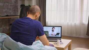 Man during coronavirus quarantine consulting with doctor via video call.